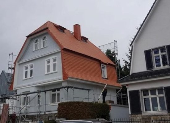 Villa mit neu eingedecktem rot-orangem Ziegeldach und Gerüst